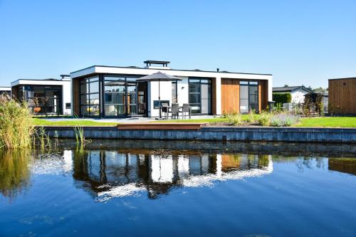 a house with a lake in front of it at Villa Nautica | 4 Pers. in Loosdrecht