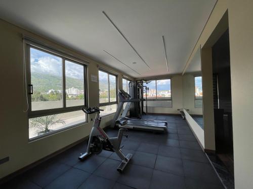 een kamer met een fitnessruimte met een loopband en ramen bij Hotel Catena in Cochabamba