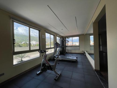 une salle de sport avec un tapis roulant et des fenêtres dans l'établissement Hotel Catena, à Cochabamba