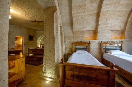 a bedroom with two beds in a stone building at Roma Cave Suite in Goreme