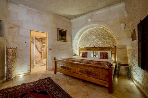 a bedroom with a large bed in a stone wall at Roma Cave Suite in Goreme