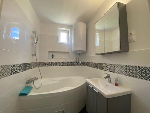 a bathroom with a tub and a sink and a mirror at Sárdoár Vendégház in Abádszalók