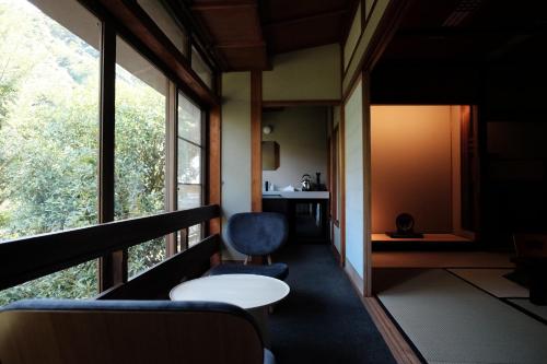 a room with a chair and a table and windows at Kobayashiya -Kinosaki Onsen- in Toyooka