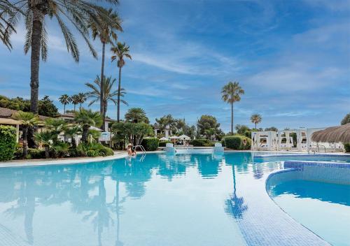 a swimming pool at a resort with palm trees at Blau Colònia Sant Jordi in Colonia Sant Jordi