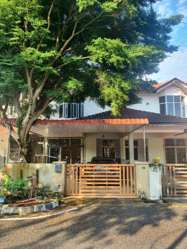 a house with a wooden gate and a tree at Homestay Pohon Rendang in Balik Pulau