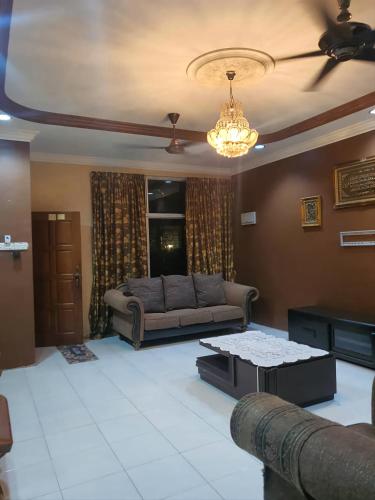 ein Wohnzimmer mit einem Sofa und einem Tisch in der Unterkunft Homestay Pohon Rendang in Balik Pulau