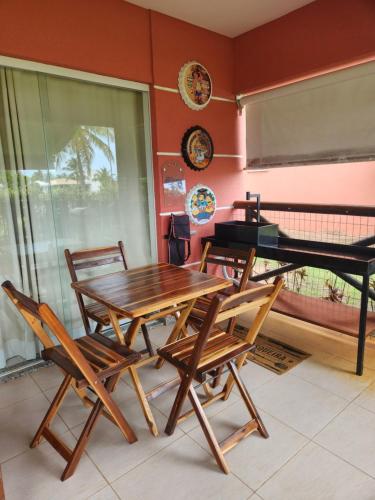 uma mesa e cadeiras de madeira e um piano numa sala em Apartamento na Praia do Saco - Condomínio Villa das Águas em Estância