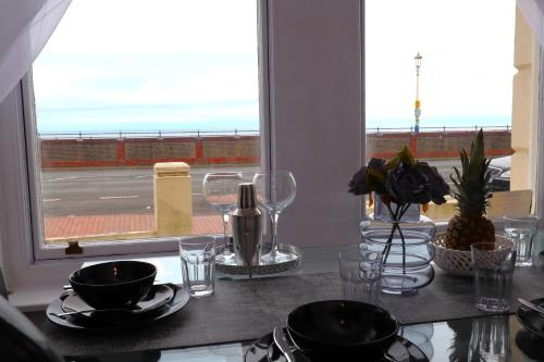 a table with plates and glasses and a window at Bliss on the Bay in Eastbourne