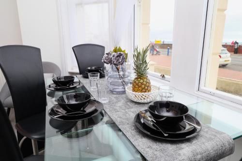 a glass table with black dishes and a pineapple on it at Bliss on the Bay in Eastbourne