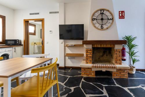 a living room with a fireplace and a clock on the wall at Apartamentos Rurales la Campiña in Casiñas Bajas