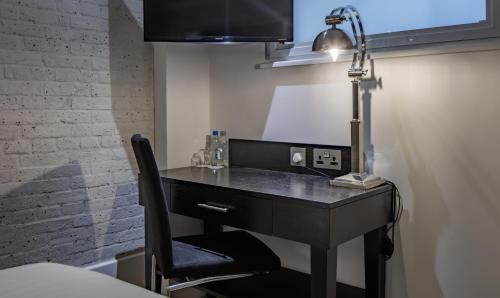 a desk with a lamp and a chair in a room at Doubletree By Hilton London - Greenwich in London