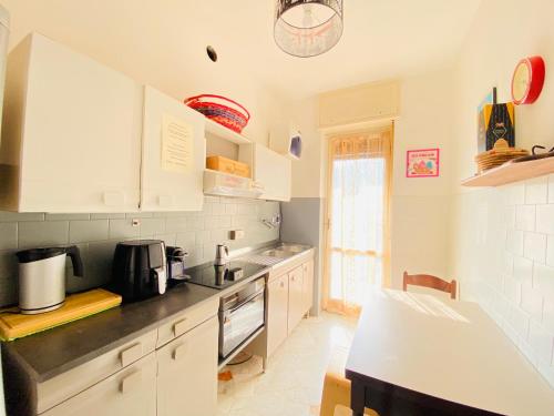 una cucina con armadi bianchi e piano di lavoro di Milano relax family house a Brugherio