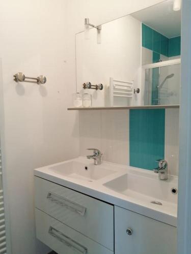 une salle de bain blanche avec un lavabo et un miroir dans l'établissement Au Bon ENdrOIT, à Barneville-Carteret