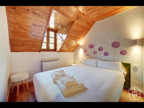 a bedroom with a large white bed with wooden ceilings at CASA DEL VALLE de Alma de Nieve in Tredós
