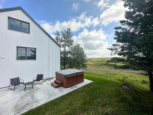 a house with two chairs and a tub on a patio at Urriðafoss Waterfall Villa in Selfoss