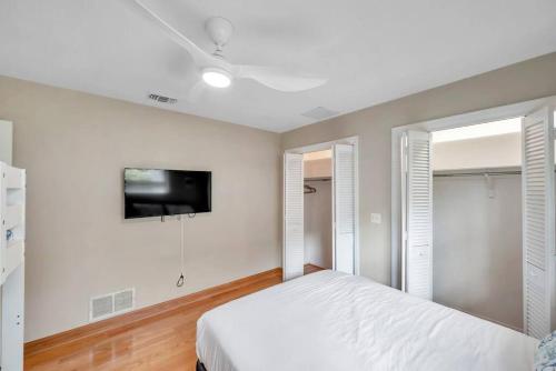 a white bedroom with a bed and a flat screen tv at Heated Pool House: Beach 3Miles · Bar · BBQ & GYM! in Largo