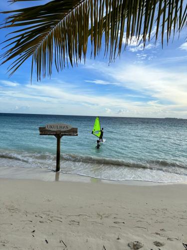 a person on a surfboard with a green sail in the ocean at Beach Veli in Ukulhas