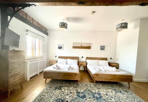two beds in a room with a tv and a rug at The Cart Lodge at Lee Wick Farm Cottages & Glamping in Saint Osyth