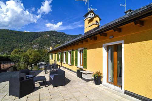 a yellow building with chairs and a clock tower at La Terrazza in Malesco