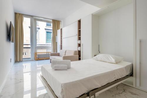 a white bedroom with a bed and a living room at LUVI - Duomo in Milan