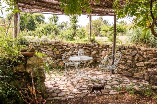 a patio with a table and chairs and a stone wall at Glicine in Montieri