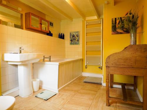 a yellow bathroom with a sink and a tub and a sink at Pass the Keys Traditional 19th C Stone Cottage in Talybont