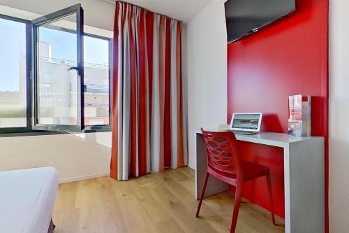 Habitación con escritorio y pared roja. en City Résidence Ivry en Ivry-sur-Seine