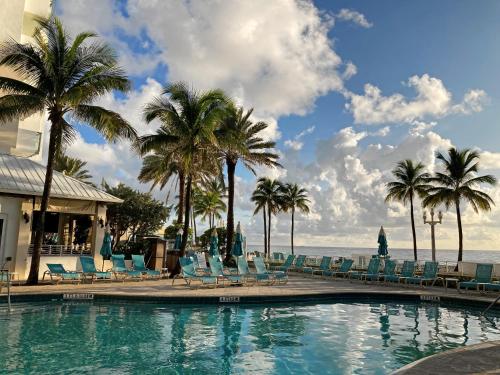 - une piscine avec des chaises longues, des palmiers et l'océan dans l'établissement Hollywood Beach Marriott, à Hollywood