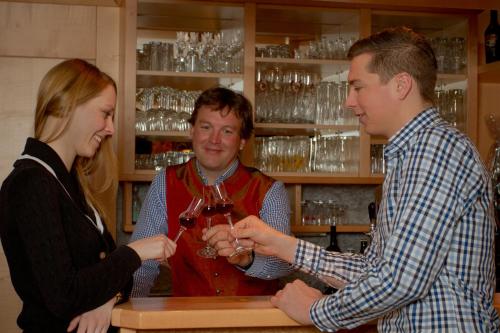 two men and a woman standing at a bar drinking wine at Brandstätterhof in Schladming