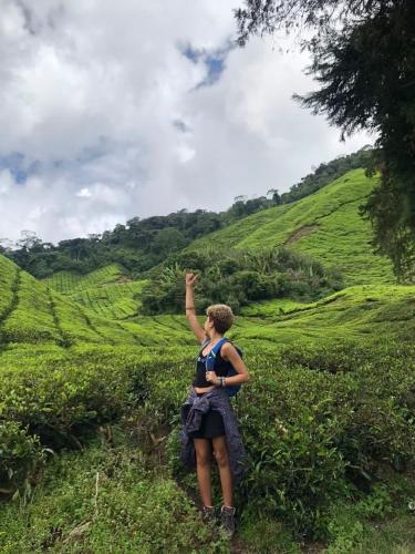 a woman standing in a field with her hand in the air at A3A Oastel CoLiving in Tanah Rata
