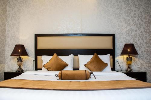 a bedroom with a large bed with two lamps at Centaurus Hotel Suites in Islamabad