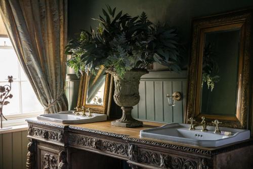 a bathroom with two sinks and a vase with a plant at The Townhouse Sherborne in Sherborne