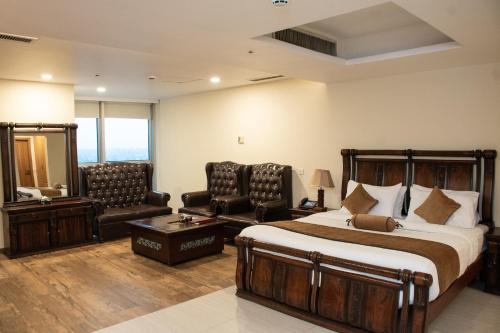 a hotel room with a bed and two chairs at Centaurus Hotel Suites in Islamabad