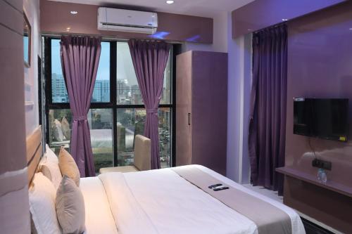 a hotel room with a large bed and a large window at Hotel Czar Inn in Surat