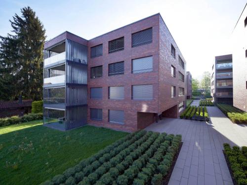 a brick building with a garden in front of it at City Apartments in Zug