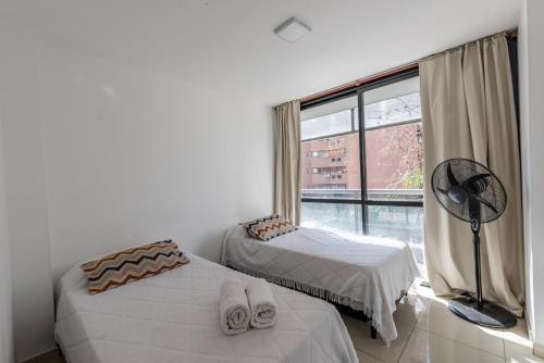 a bedroom with two beds and a window with a fan at Independencia Nva Cba para 6 personas in Córdoba
