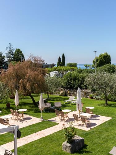 a park with tables and chairs and umbrellas at Hotel Ca' Mura in Bardolino
