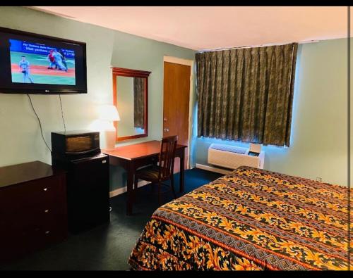 een hotelkamer met een bed, een bureau en een televisie bij Economy Inn of Greenville, Near ECU Health Center in Greenville