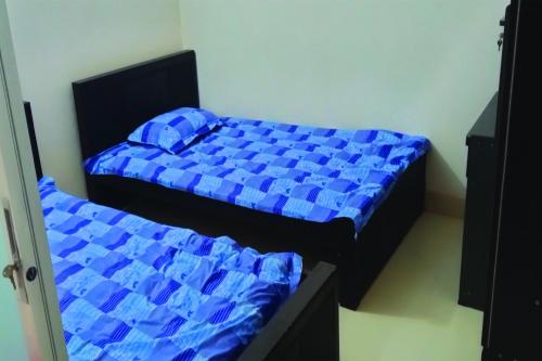 two beds with blue sheets in a room at Smart Hostel in Dhaka