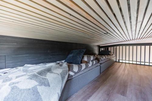 Cama grande en habitación con techo de madera en Villa Mommo II, en Rovaniemi