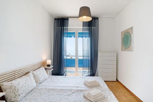 a white bedroom with a bed and a window at Margherita in Ospedaletti
