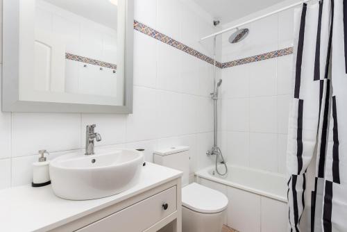a white bathroom with a sink and a toilet at Bahia cozy ocean view suite in Puerto de Santiago