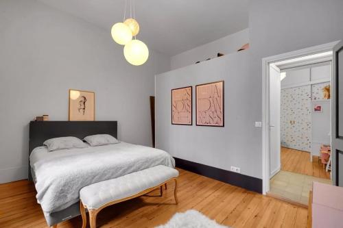 een witte slaapkamer met een bed en een bank bij Bleu du Maine - Elegant T3 avec terrasse in Toulouse
