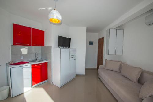 uma sala de estar com um sofá e uma cozinha com armários vermelhos em M&M Apartments em Utjeha