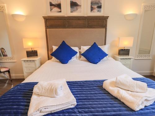 a bedroom with a bed with blue pillows and towels on it at Le Chalet in Elterwater