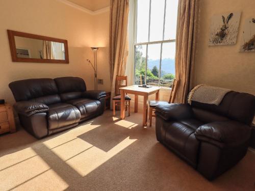 a living room with a leather couch and a table at Easedale in Grasmere