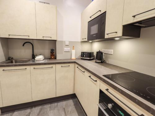 a kitchen with white cabinets and a sink at Easedale in Grasmere