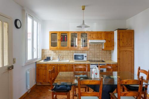 une cuisine avec des armoires en bois et une table avec des chaises dans l'établissement La Maison Kokliko - Maison pour 4, à Saint-Leu-la-Forêt