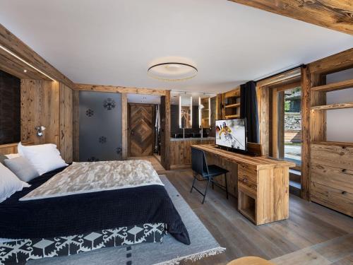 a bedroom with a bed and a desk with a television at Chalet de luxe familial à Val d'Isère avec spa, proche des pistes et équipements premium - FR-1-567-72 in Val dʼIsère