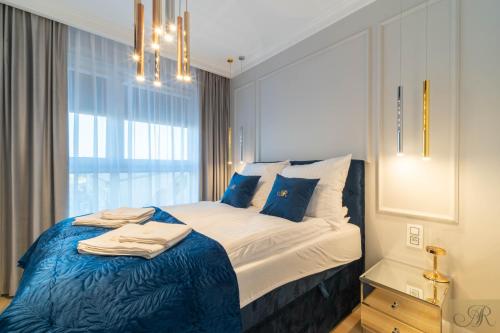 a bedroom with a bed with blue sheets and a window at Apartament Rosa Stacja Mińsk in Mińsk Mazowiecki